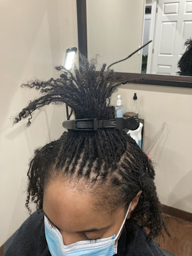 A woman with a mask on her head is getting her hair cut